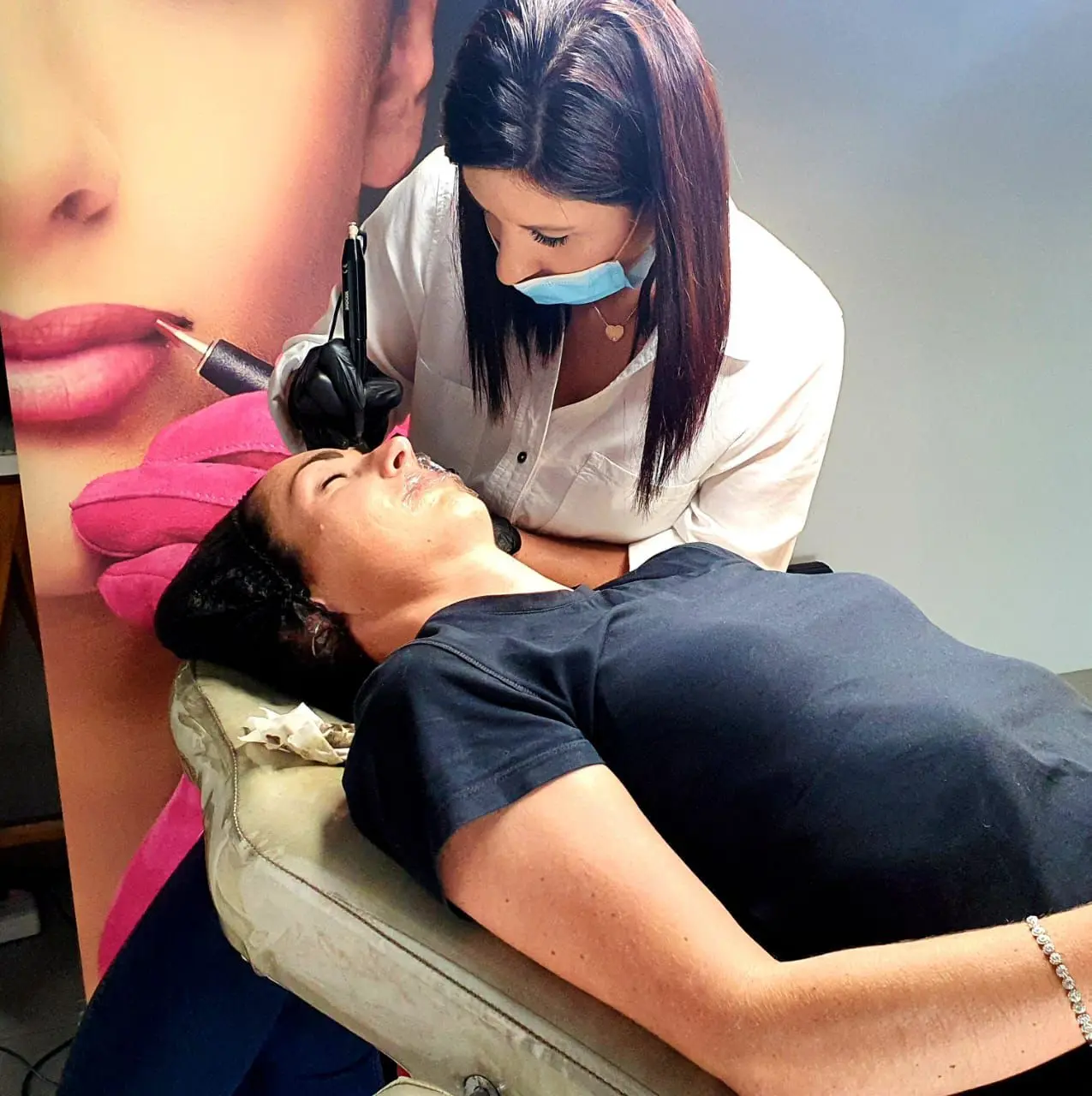 Permanent makeup artist applying pigment during a lip treatment session.